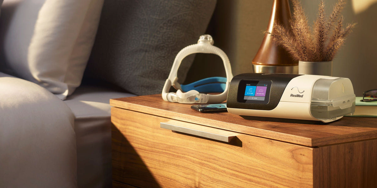 Bedroom scene with a bed, nightstand, lamp and Resmed Airsense 11.