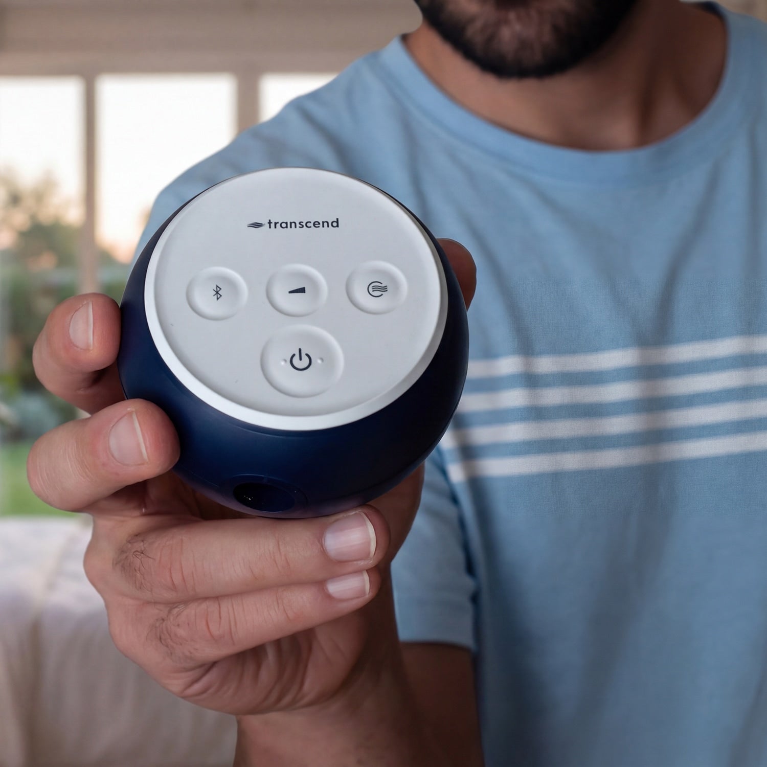 A person in a light blue t-shirt holds a Transcend CPAP in their hand