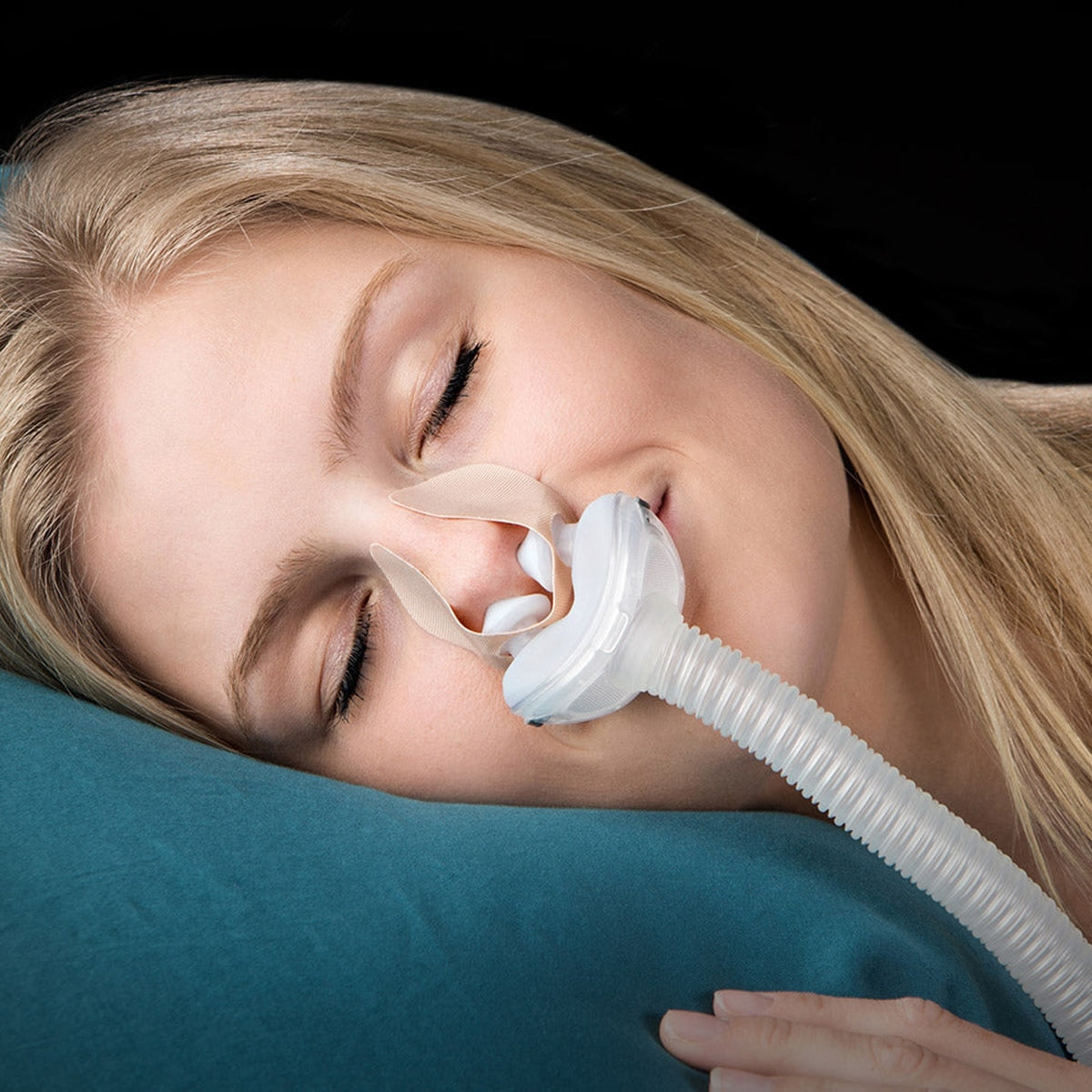 Woman wearing a nasal pillow mask with nozseal adhesive strips