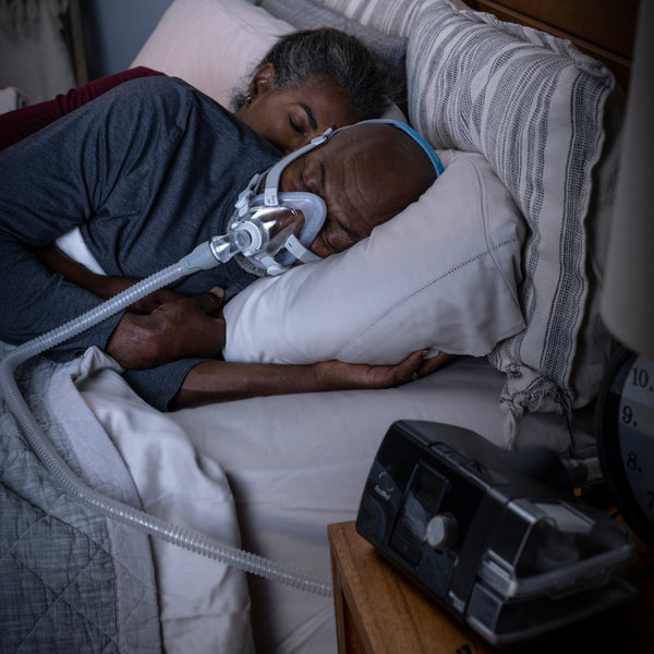 Person sleeping with an AirSense 10 CPAP machine in a bedroom setting