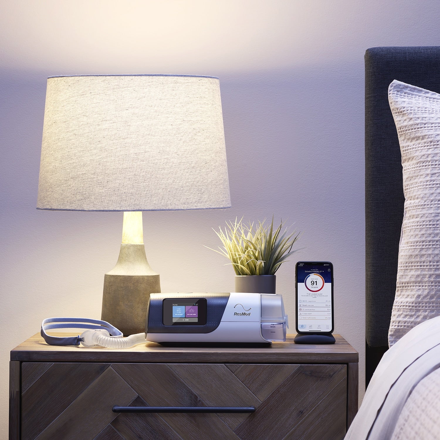Airsense 11 Autoset on a wooden nightstand with a lamp and books in a bedroom setting