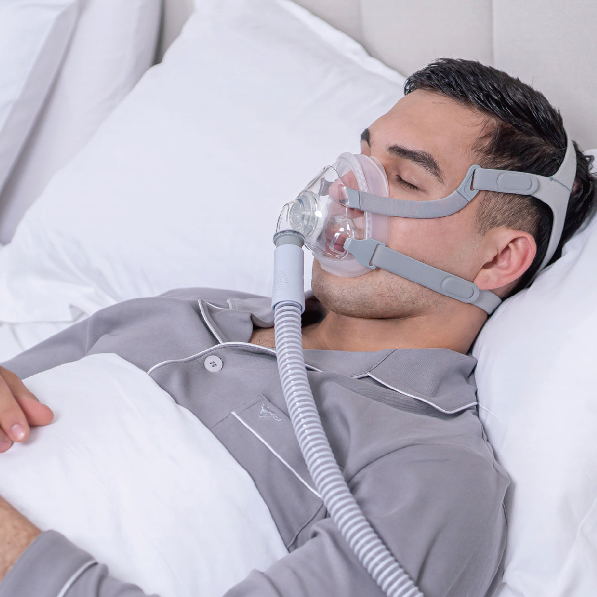 Man wearing a CPAP mask and hose in bed