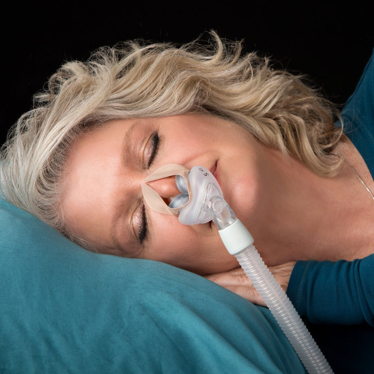 Woman wearing a nasal pillow mask with nozseal adhesive strips