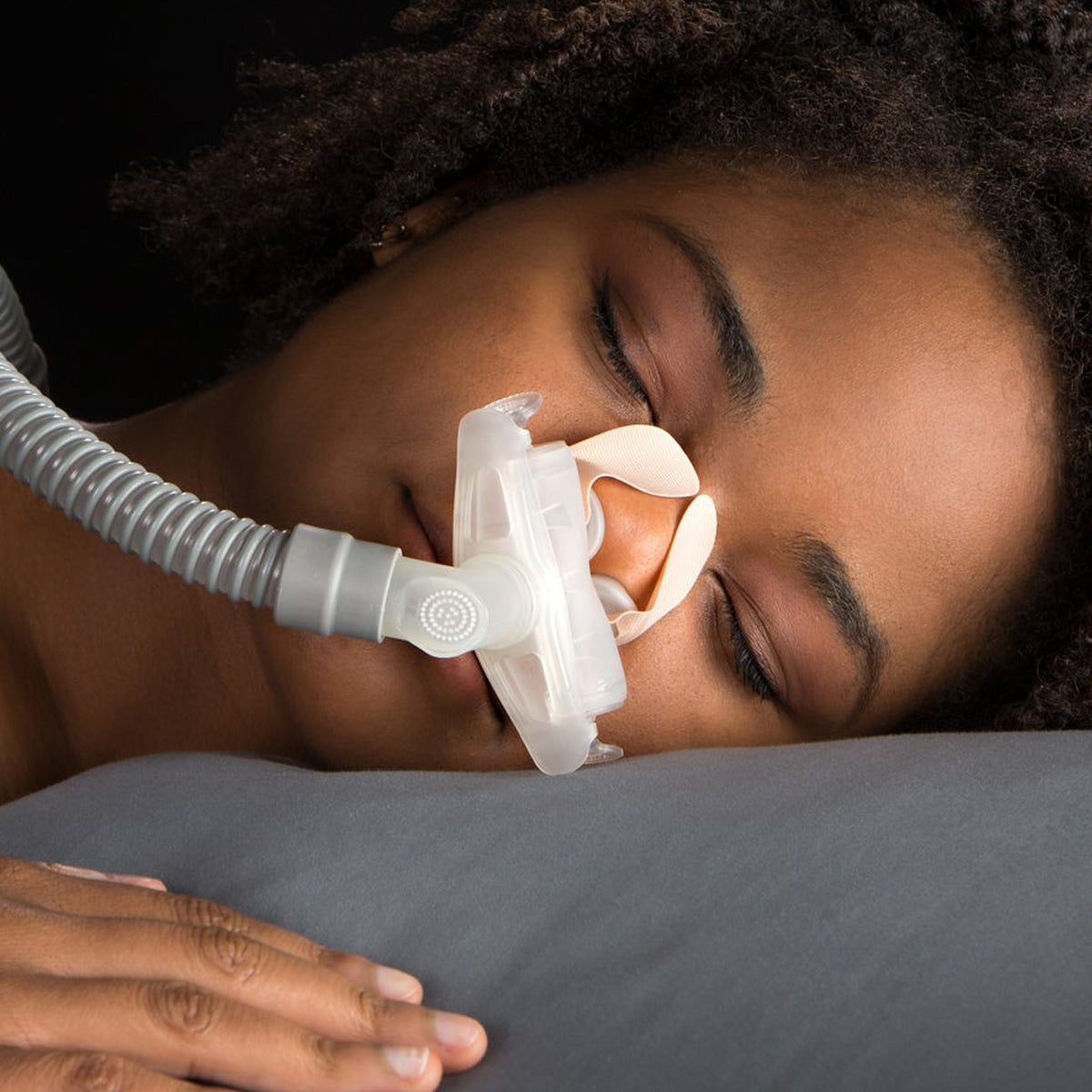 Woman wearing a nasal pillow mask with nozseal adhesive strips